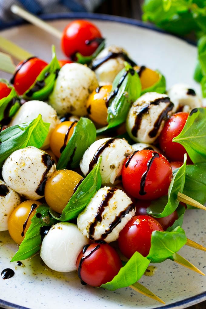 Caprese Skewers | Caprese Kabobs | Caprese Appetizer #tomato #mozzarella #basil #caprese #appetizer #edsug A plate of caprese skewers with mozzarella, tomatoes and basil.