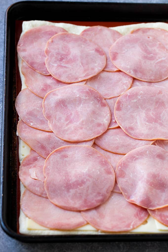 Ham and Cheese Pinwheels Recipe | Ham and Cheese Roll Ups | Ham and Cheese Rolls | Ham and Cheese Bread Rolls #ham #cheese #appetizer #pinwheels #edsug Slices of ham and cheese on top of dough.