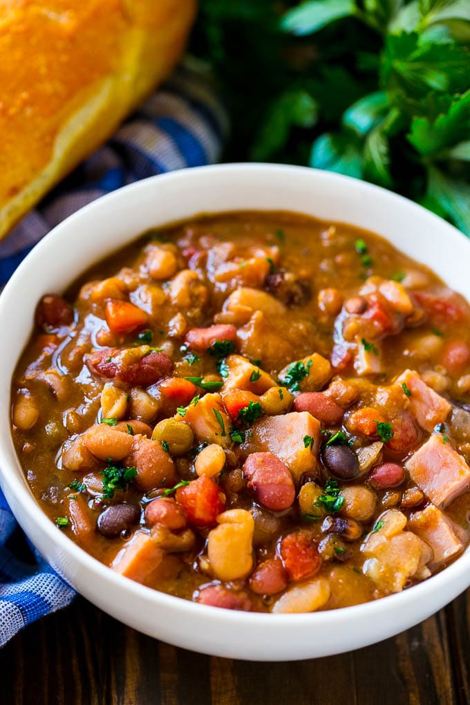 Slow Cooker Ham Bone Soup | Ham and Bean Soup | Ham Bone and Bean Soup | Ham Soup | Leftover Ham Recipe #ham #hamsoup #leftoverham #soup #slowcooker #crockpot #edsug Crock pot ham bone soup in a bowl topped with parsley.