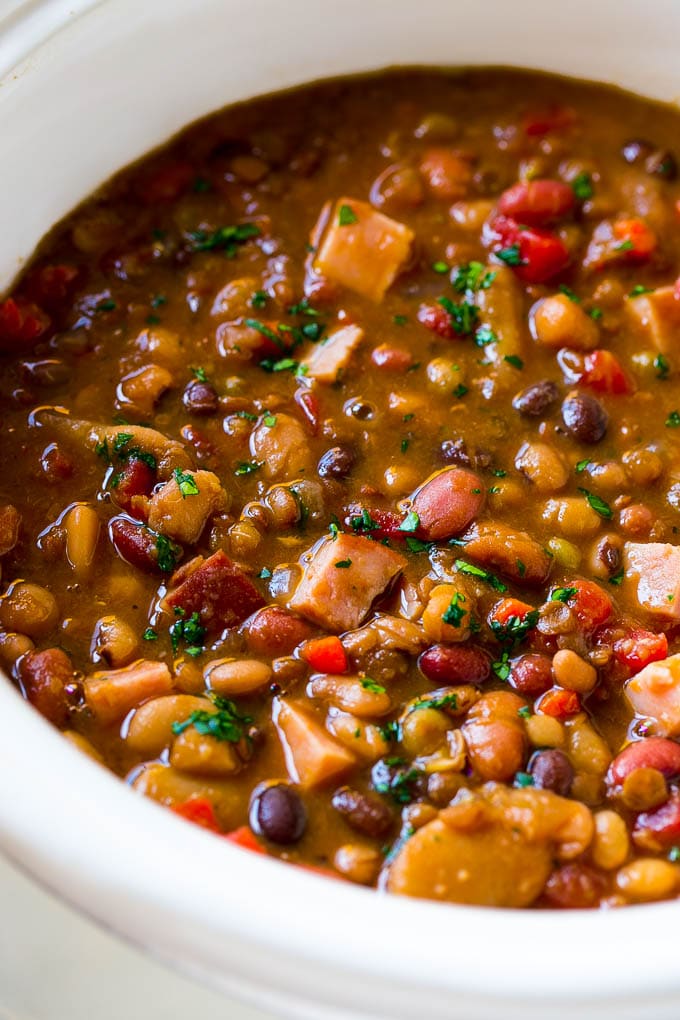 Slow Cooker Ham Bone Soup | Ham and Bean Soup | Ham Bone and Bean Soup | Ham Soup | Leftover Ham Recipe #ham #hamsoup #leftoverham #soup #slowcooker #crockpot #edsug A slow cooker full of soup with parsley on top.