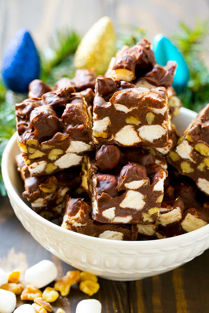 Rocky Road Fudge | Chocolate Marshmallow Fudge | Chocolate Nut Fudge | Microwave Fudge #fudge #chocolatefudge #nobake #chocolate #dessert #rockyroad #edsug A bowl of fudge squares with holiday decorations in the background.