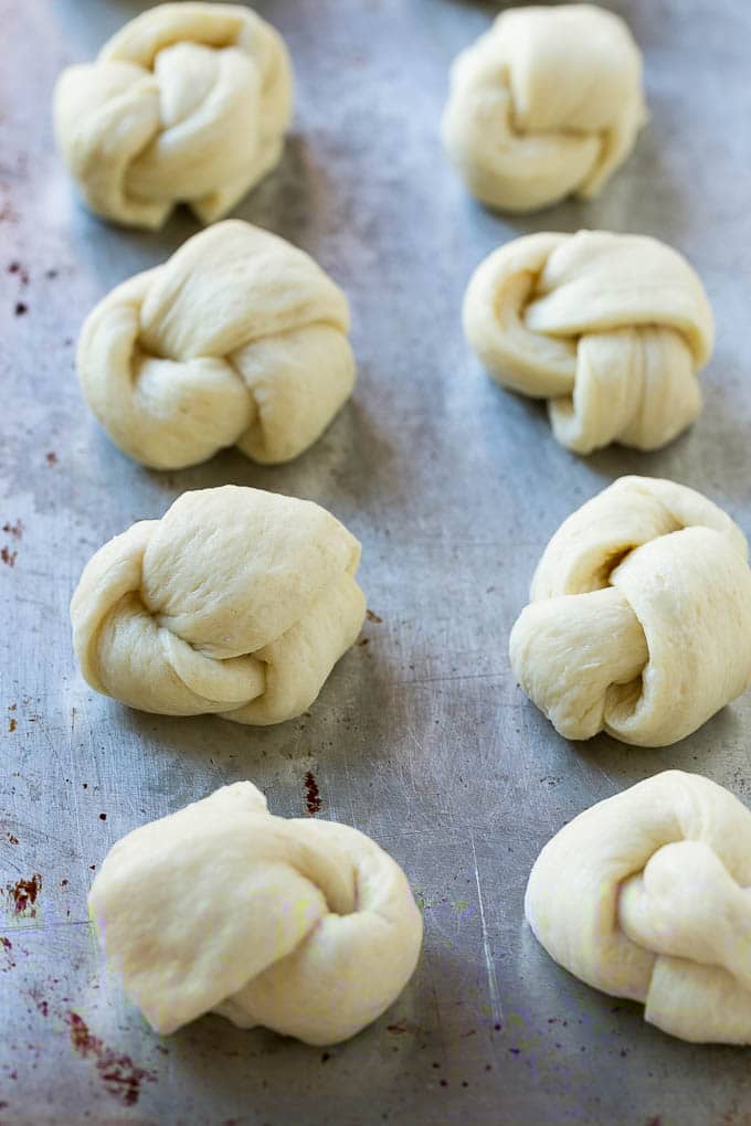 Garlic Knots Recipe | Garlic Rolls | Garlic Butter Rolls | Garlic Bread Recipe #garlic #garlicbread #garlicknots #breadsticks #edsug Pizza dough tied up and placed on a sheet pan.