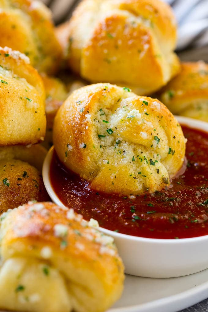 Garlic Knots Recipe | Garlic Rolls | Garlic Butter Rolls | Garlic Bread Recipe #garlic #garlicbread #garlicknots #breadsticks #edsug A garlic roll being dipped into marinara sauce for a delicious finishing touch.