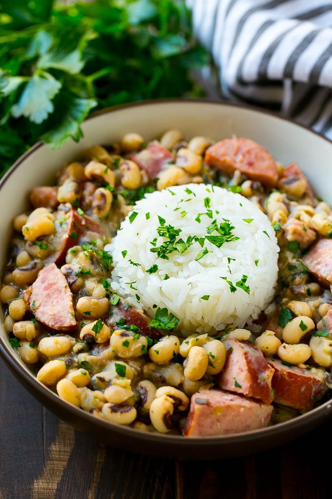 Slow Cooker Black Eyed Peas Recipe | Crock Pot Black Eyed Peas | Southern Black Eyed Peas | Black Eyed Peas with Ham | Black Eyed Peas with Sausage #blackeyedpeas #slowcooker #crockpot #sausage #newyears #dinner #edsug A bowl of slow cooker black eyed peas with a scoop of rice.