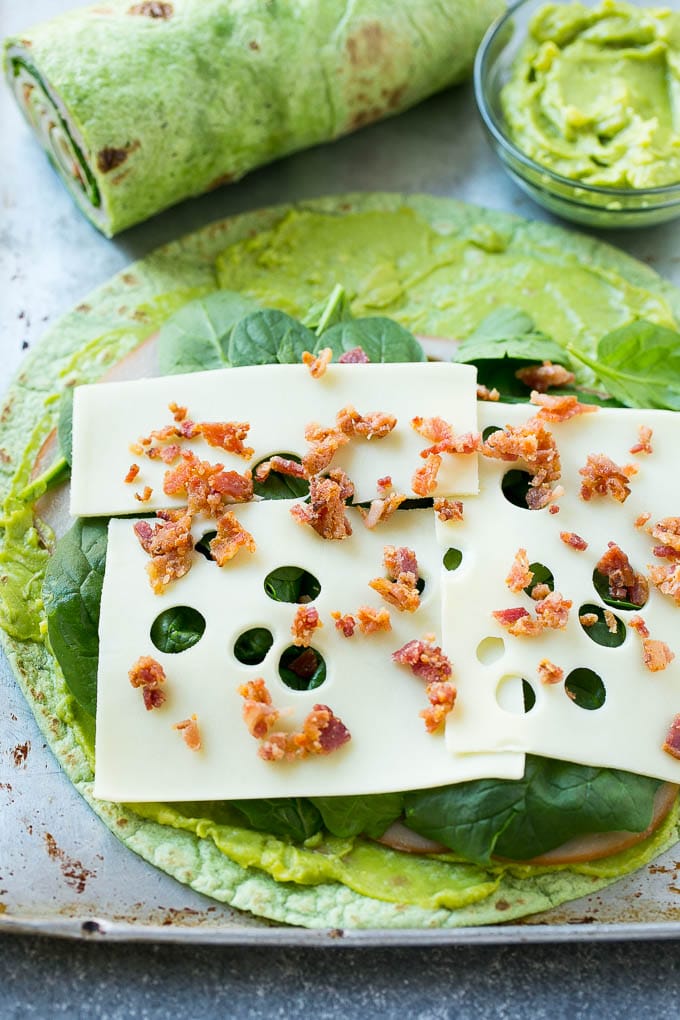 Turkey Roll Ups Recipe | Turkey Pinwheel Sandwiches | Turkey Roller Sandwiches #turkey #avocado #sandwich #lunch #appetizer #edsug A spinach tortilla layered with turkey, spinach, cheese and bacon.