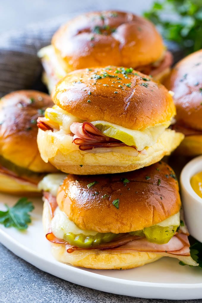 Cuban Sliders Recipe | Cuban Sandwich Recipe | Slider Sandwiches | Ham and Cheese Sliders #sliders #sandwiches #ham #cheese #appetizer #edsug A pile of cuban sliders filled with ham, cheese and pickles.