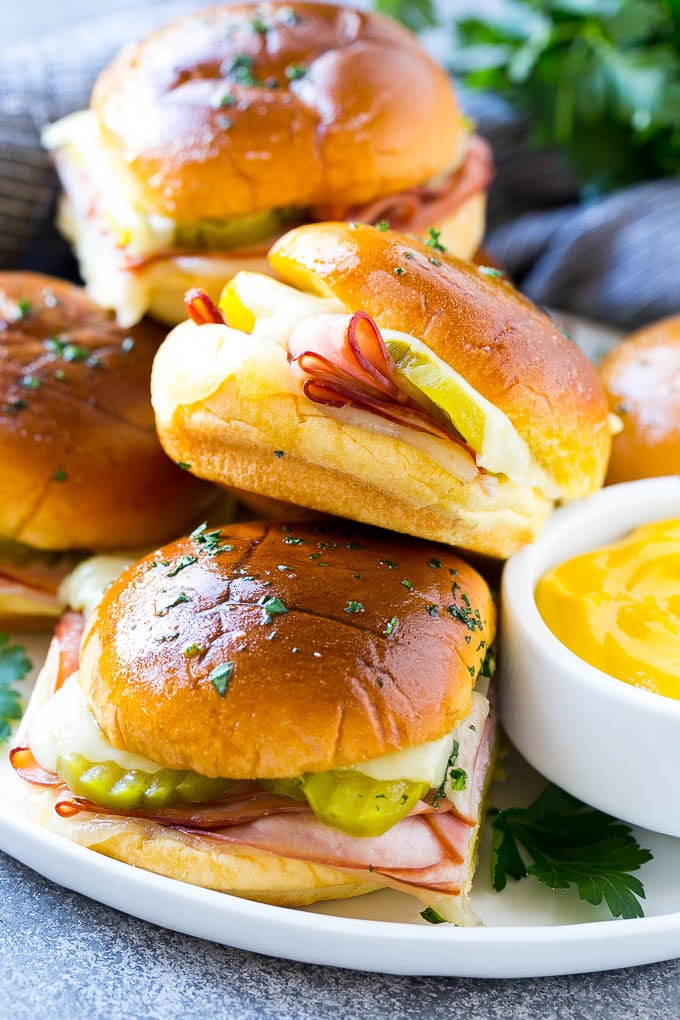 Cuban Sliders Recipe | Cuban Sandwich Recipe | Slider Sandwiches | Ham and Cheese Sliders #sliders #sandwiches #ham #cheese #appetizer #edsug A plate full of Cuban sliders with cheese, pickles and ham on buns.