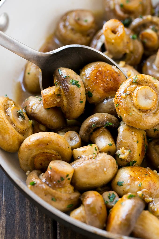 Garlic Mushrooms Recipe | Steakhouse Mushrooms | Sauteed Mushrooms | Garlic Butter Mushrooms | Mushroom Side Dish #mushrooms #butter #keto #lowcarb #dinner #sidedish #edsug A pan of sauteed garlic mushrooms with a serving spoon.