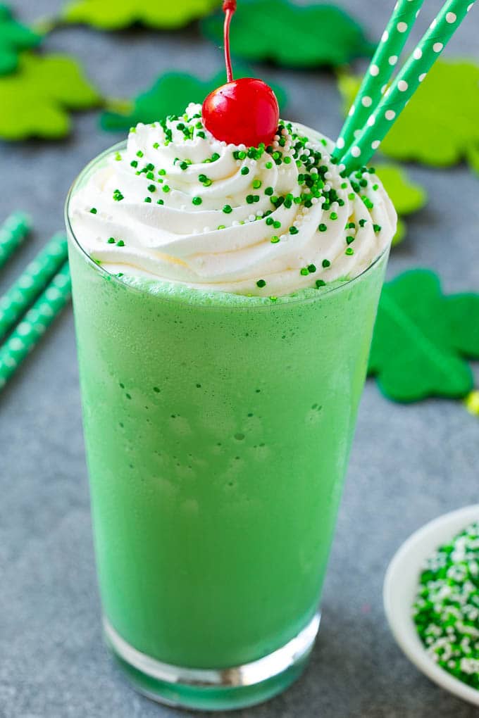 Shamrock Shake Recipe | McDonald's Shamrock Shake | Saint Patrick's Day Drink | Mint Milkshake #milkshake #stpatricksday #saintpatricksday #mint #edsug A glass of shamrock shake topped with whipped cream, sprinkles and a cherry.