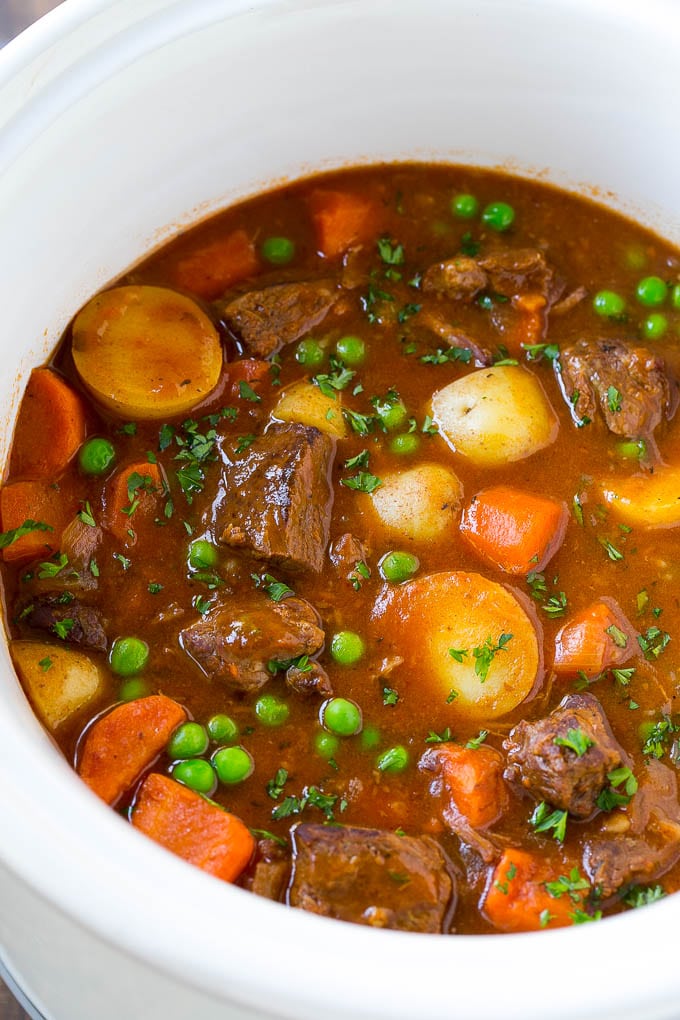 Slow Cooker Beef Stew Recipe | Beef and Potato Stew | Crock Pot Beef Stew | Easy Beef Stew #beef #beefstew #soup #slowcooker #crockpot #dinner #edsug A slow cooker full of beef stew that contains meat, potatoes, carrots and peas, all in a savory broth.