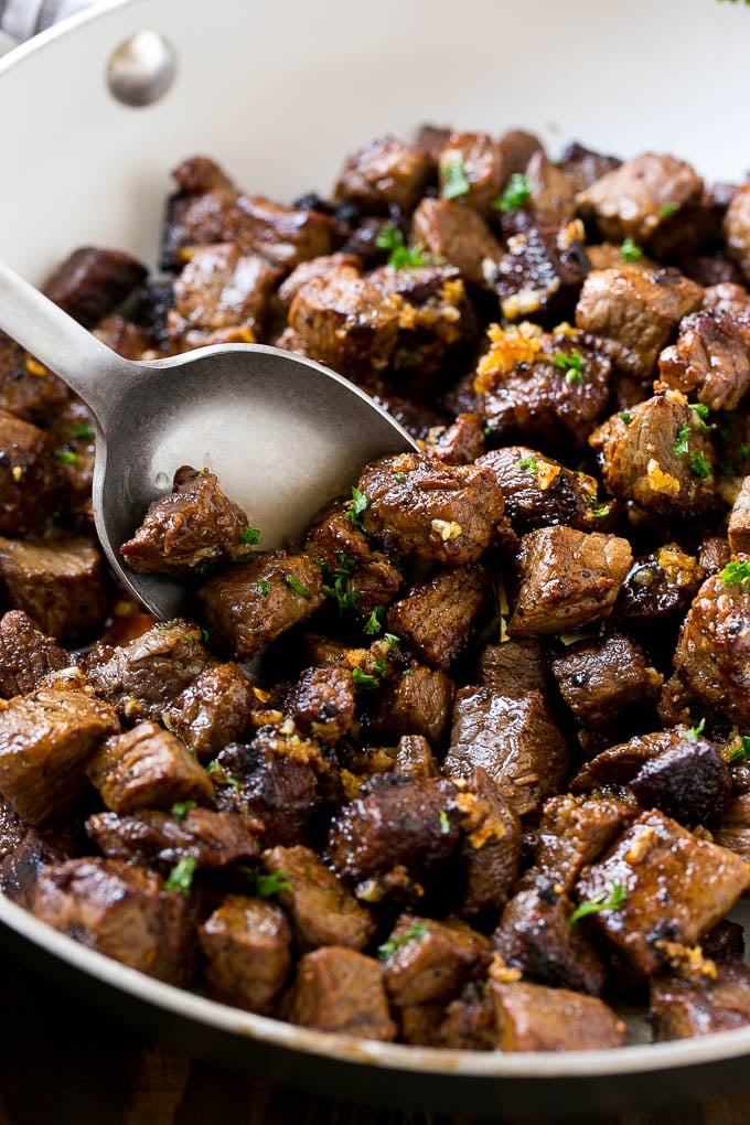 Steak Bites in Garlic Butter Recipe | Garlic Steak | Sirloin Steak Recipe | Steak Appetizer #steak #lowcarb #keto #edsug #dinner A pan of steak bites with a serving spoon.