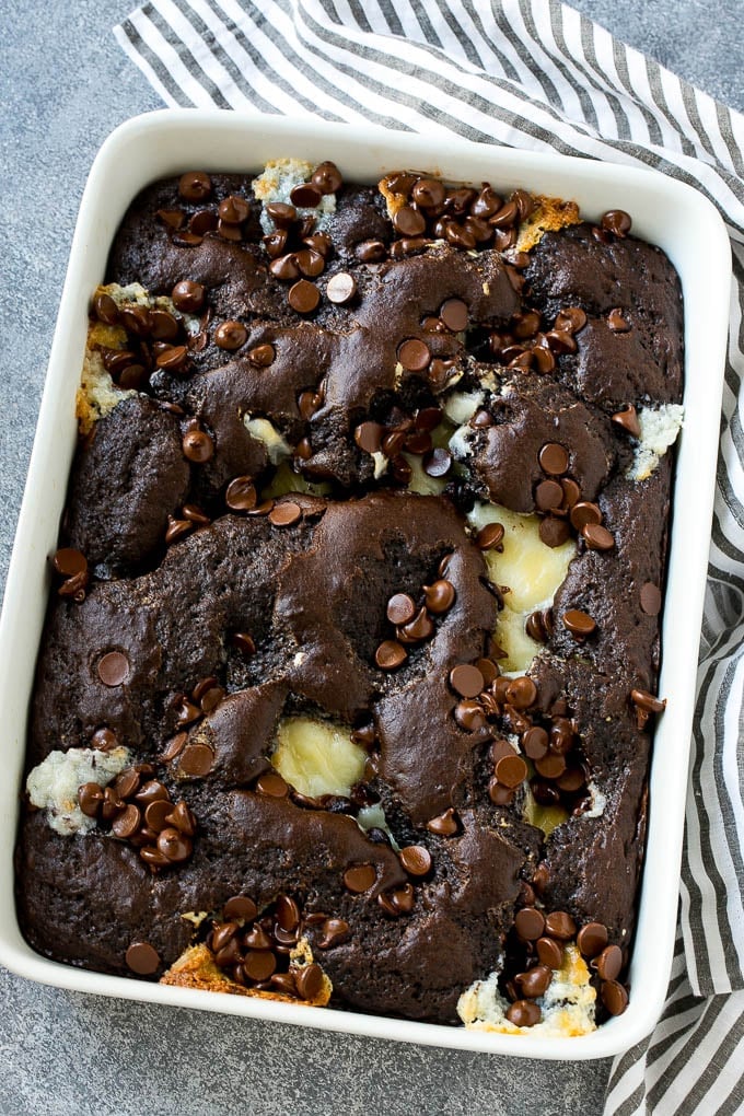 Earthquake Cake Recipe | Chocolate Cake Recipe | Chocolate Coconut Cake | Coconut Pecan Cake #cake #chocolate #coconut #pecans #dessert #chocolatecake #edsug A pan of earthquake cake topped with dollops of cream cheese and chocolate chips.