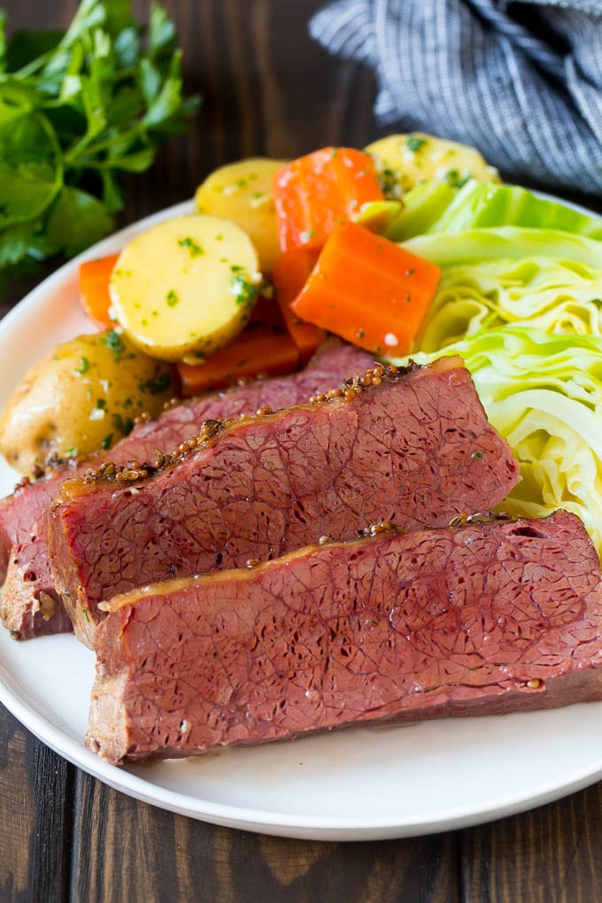 Slow Cooker Corned Beef Recipe | Crock Pot Corned Beef | Corned Beef and Cabbage #beef #cornedbeef #cabbage #potatoes #carrots #stpatricksday #irish #edsug Sliced slow cooker corned beef on a plate with carrots, potatoes and cabbage.