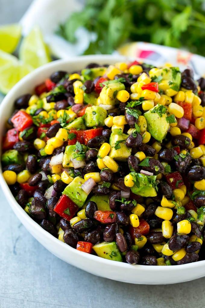 Black Bean and Corn Salad Recipe | Mexican Salad | Black Bean Salad | Bean Salad #salad #beans #corn #mexicanfood #edsug A bowl of black bean and corn salad loaded with avocado and red pepper, garnished with fresh cilantro.