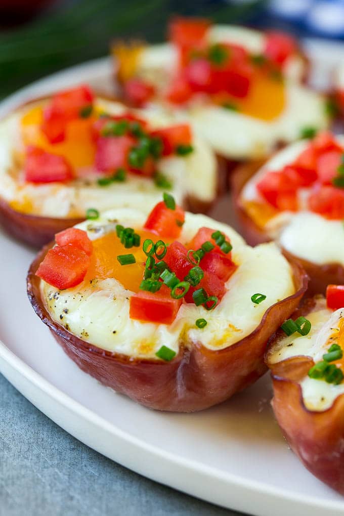Ham and Egg Cups Recipe | Low Carb Breakfast | Ham and Eggs #ham #eggs #lowcarb #breakfast #edsug A plate of ham and egg cups topped with diced tomatoes and chives.
