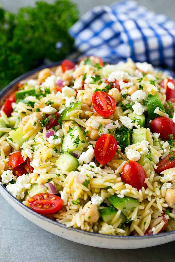 Orzo Salad Recipe | Orzo Pasta Salad | Greek Orzo Salad | Mediterranean Orzo Salad #pastasalad #orzo #greekfood #salad #edsug Orzo salad in a serving bowl with tomatoes, cucumbers and chickpeas.