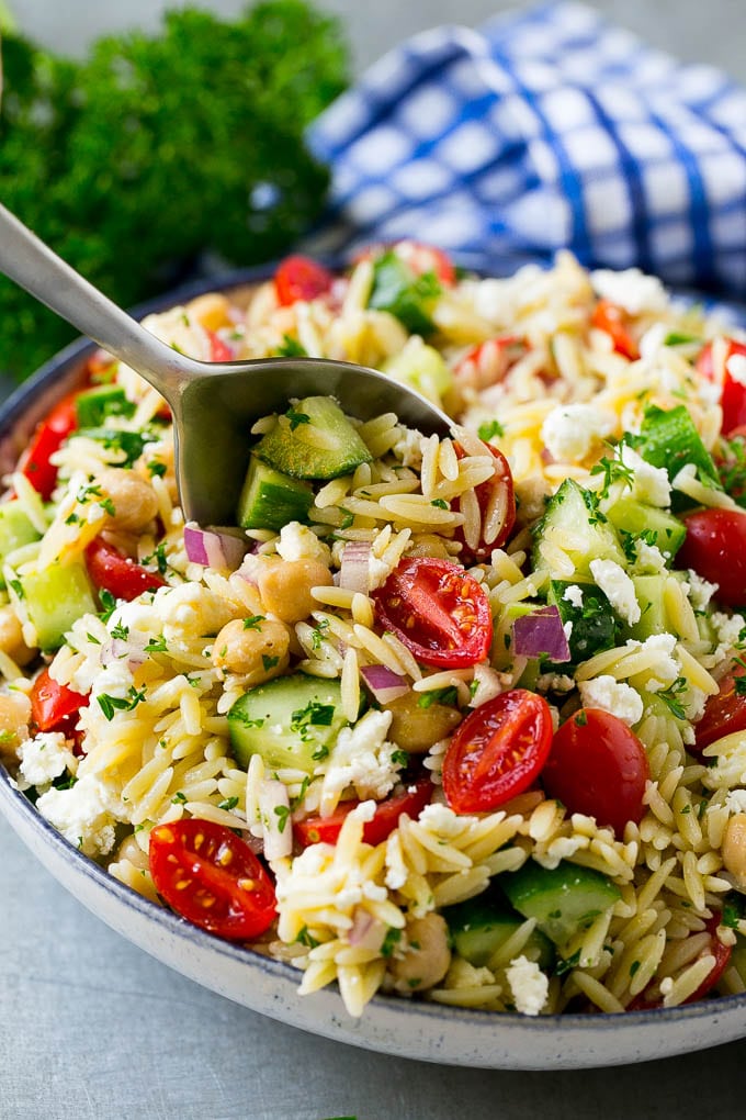 Orzo Salad Recipe | Orzo Pasta Salad | Greek Orzo Salad | Mediterranean Orzo Salad #pastasalad #orzo #greekfood #salad #edsug Orzo pasta salad with a serving spoon in the bowl.