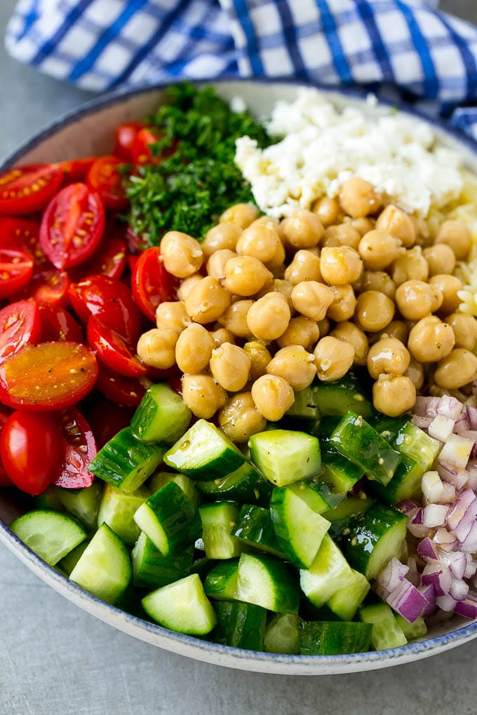 Orzo Salad Recipe | Orzo Pasta Salad | Greek Orzo Salad | Mediterranean Orzo Salad #pastasalad #orzo #greekfood #salad #edsug A bowl of orzo pasta, tomatoes, cucumbers, red onions, chickpeas and feta cheese topped with dressing.