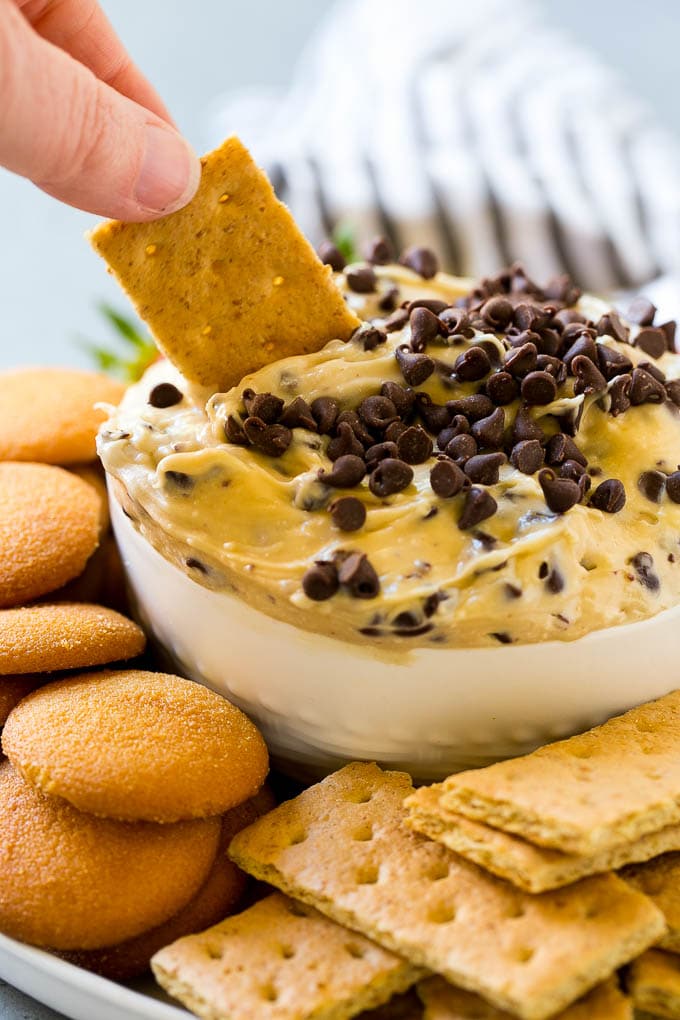 Cookie Dough Dip Recipe | Edible Cookie Dough | Chocolate Chip Cookie Dip #cookies #dip #cookiedough #dessert #snack #edsug A graham cracker dipping into a bowl of cookie dough dip.