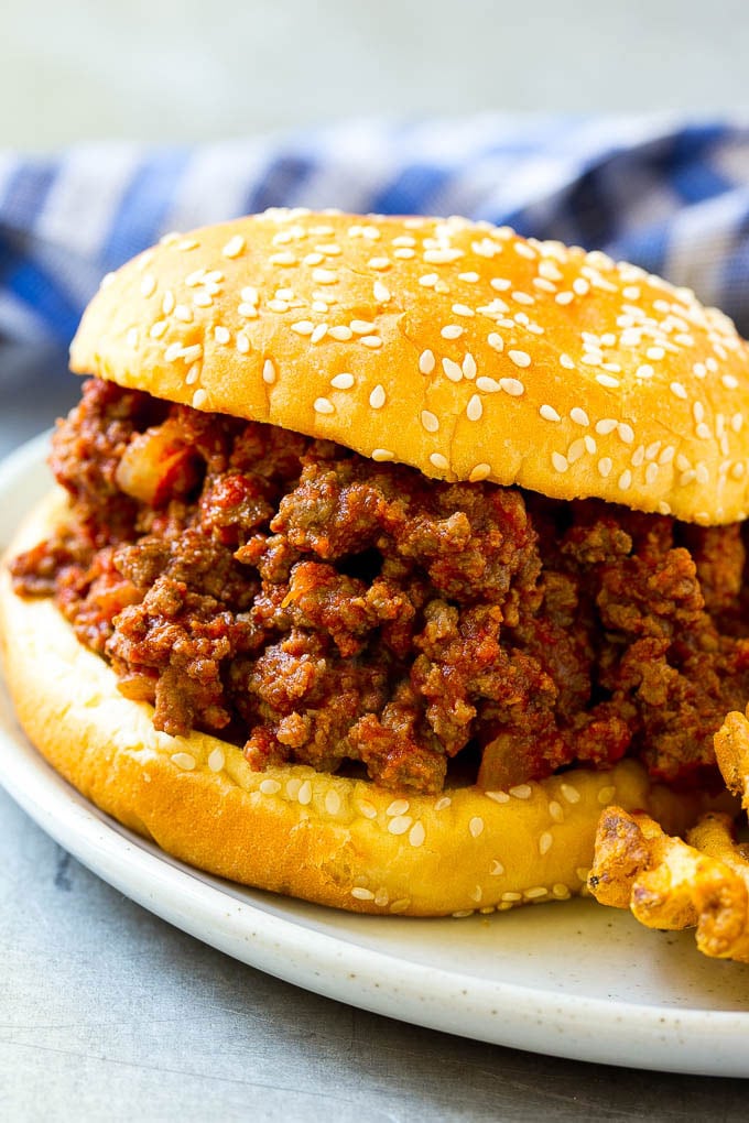 A crock pot sloppy joe on a hamburger bun served with french fries.