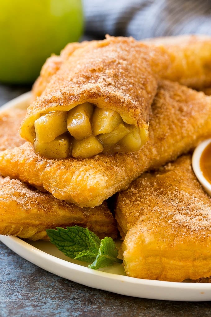 Fried Apple Pies Recipe | McDonald's Copycat Recipe | Apple Pie | Apple Hand Pies #pie #apples #applepie #dessert #snack #edsug Fried apple pies on a plate served with caramel sauce and topped with cinnamon sugar.