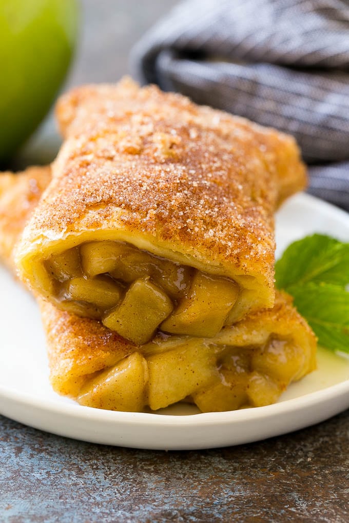 Fried Apple Pies Recipe | McDonald's Copycat Recipe | Apple Pie | Apple Hand Pies #pie #apples #applepie #dessert #snack #edsug A cross section of a fried apple pie on a plate.