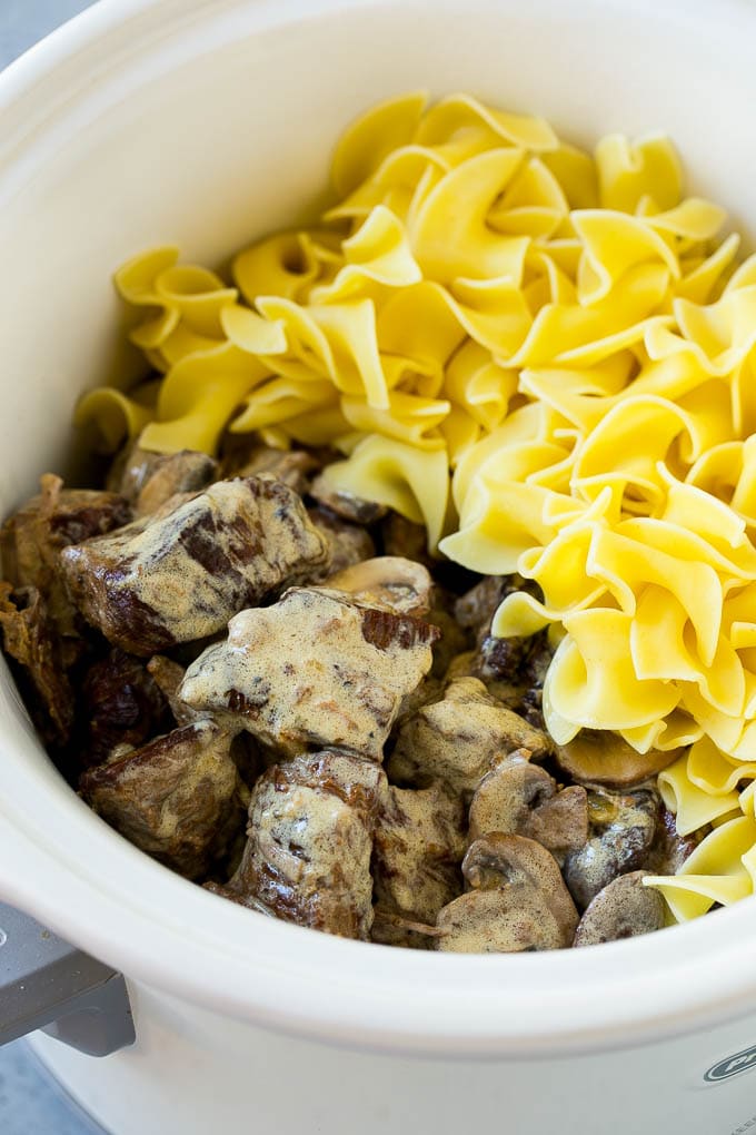 Slow Cooker Beef Stroganoff Recipe | Crock Pot Beef Stroganoff | Beef Recipe #slowcooker #crockpot #beef #mushrooms #pasta #dinner #edsug Beef in a creamy sauce and egg noodles in a slow cooker.
