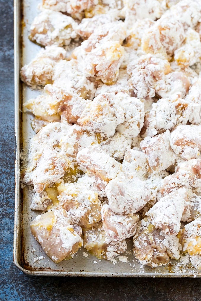 Sweet and Sour Chicken Recipe | Chinese Food Copycat Recipe | Chicken with Pineapple #chicken #chinesefood #pineapple #stirfry #takeout #dinner #edsug Chicken pieces coated in egg and flour on a baking sheet.