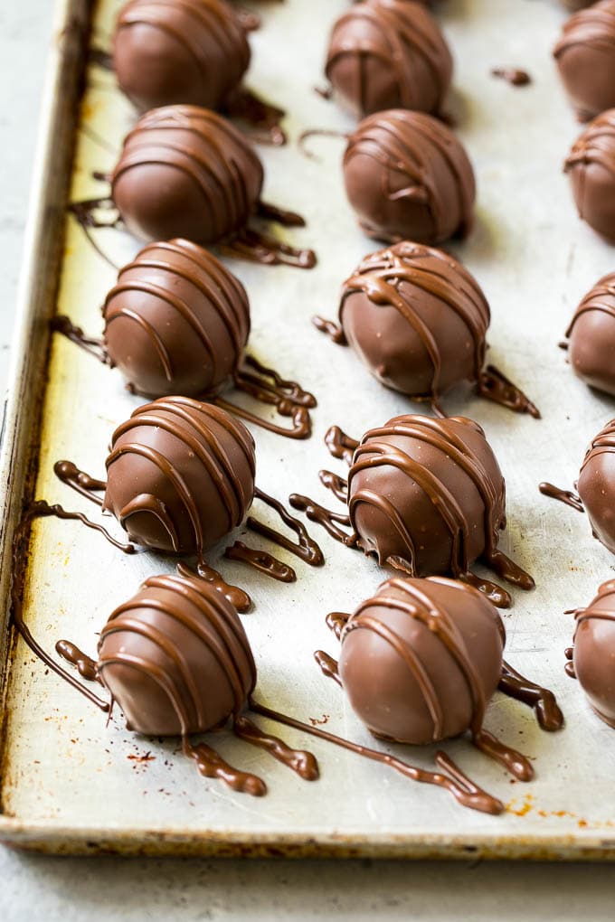 Chocolate Covered Cherries Recipe | Cherry Cordials | Cherry Candy #chocolate #candy #dessert #cherry #sweets #edsug Chocolate covered cherries on a sheet pan with a chocolate drizzle on top.