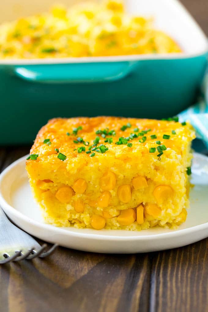 Corn Pudding Recipe | Corn Casserole | Corn Side Dish #corn #pudding #casserole #sidedish #thanksgiving #dinner #edsug A serving of corn pudding on a plate, garnished with chives.