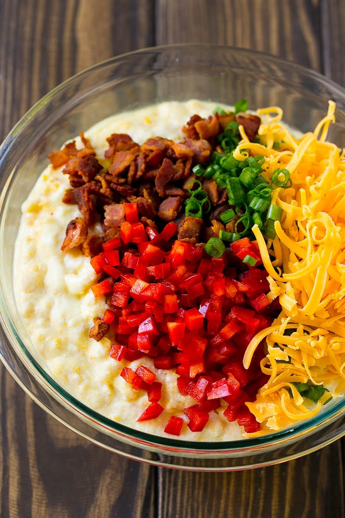 Loaded Corn Casserole Recipe | Easy Corn Casserole | Bacon Corn Casserole | Corn Pudding #corn #casserole #bacon #cheese #sidedish #thanksgiving #dinner #edsug A bowl of batter with red pepper, green onions, cheddar cheese and bacon.