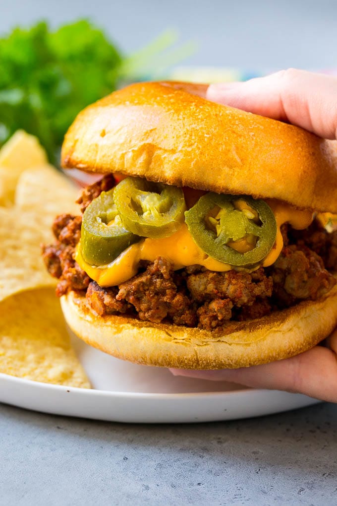 A nacho sloppy joe being held by a hand.
