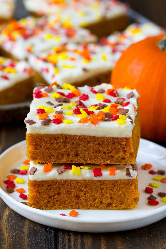 Pumpkin Bars Recipe | Pumpkin Cake | Pumpkin Dessert #pumpkin #fall #dessert #edsug #thanksgiving A stack of pumpkin bars topped with frosting and sprinkles.