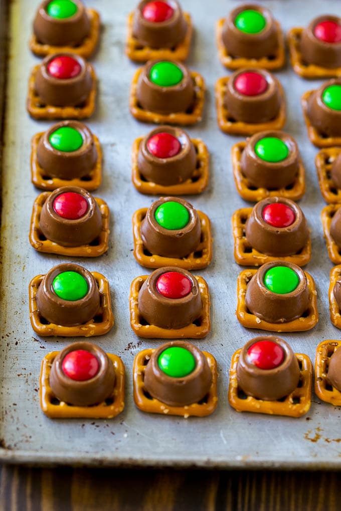 Rolo Pretzels Recipe | Chocolate Pretzels | Caramel Pretzels | Holiday Candy #christmas #baking #dessert #candy #chocolate #caramel #pretzels #edsug Treats with red and green M&M's pressed on top all on a baking sheet.