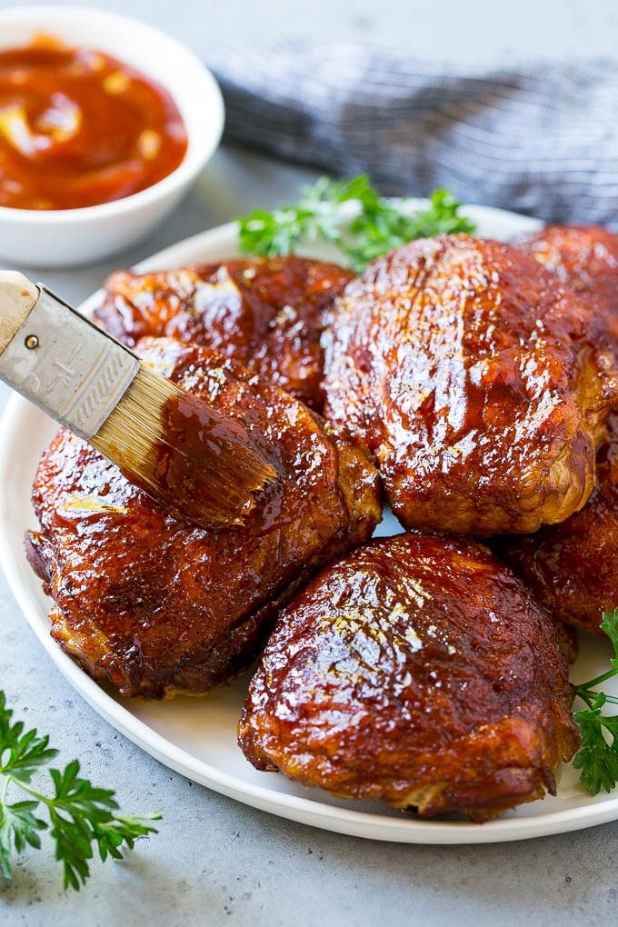 Smoked Chicken Thighs Recipe | Barbecue Chicken Thighs | Easy Chicken Thighs #chicken #barbecue #smoker #dinner #edsug A plate of smoked chicken thighs being basted with barbecue sauce.