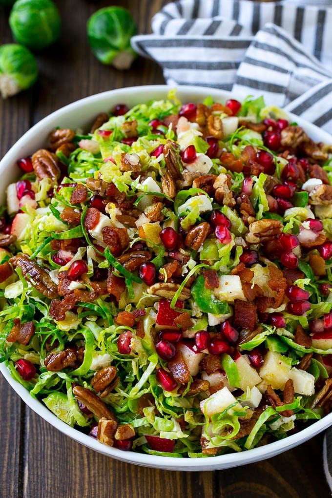 Brussels Sprout Salad Recipe | Shredded Brussels Sprouts Salad | Fall Salad #salad #brusselssprouts #bacon #thanksgiving #pomegranate #apple #dinner #edsug A bowl of salad made with pomegranate, bacon and apples.