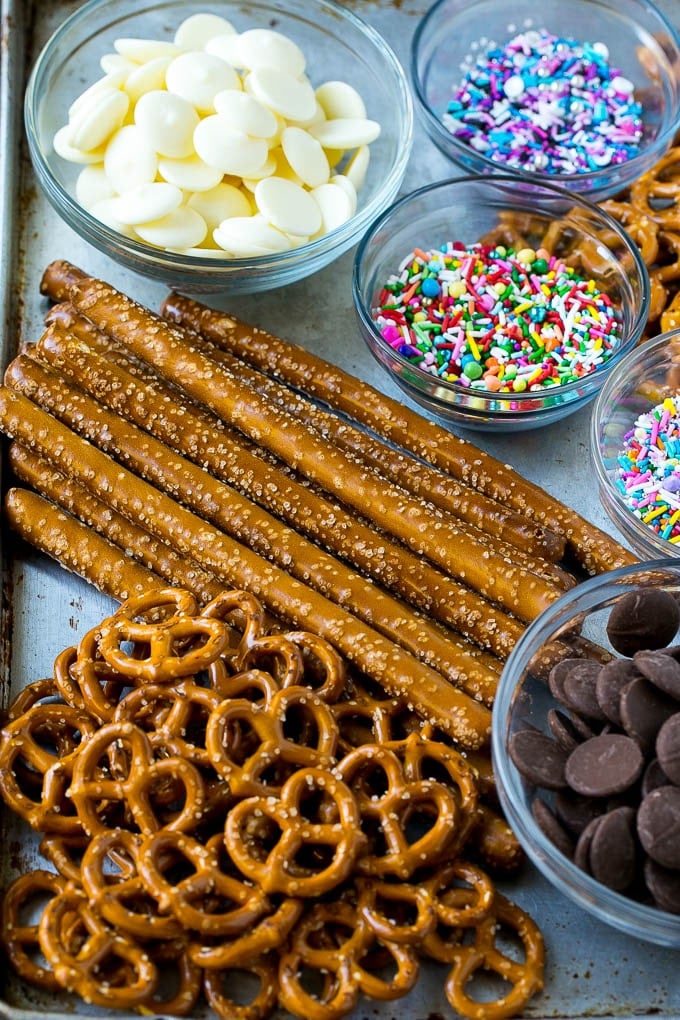 Chocolate Covered Pretzels Recipe | Sprinkle Pretzels | No Bake Dessert #pretzels #chocolate #christmas #sprinkles #candy #edsug Ingredients including candy melts and sprinkles on a sheet pan.