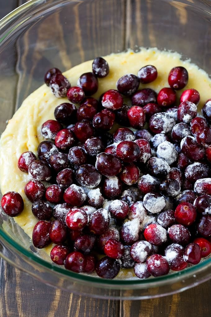 Cranberry Bread Recipe | Cranberry Loaf | Cranberry Orange Bread #cranberry #bread #baking #dessert #fall #edsug Orange batter topped with a pile of fresh cranberries in a mixing bowl.