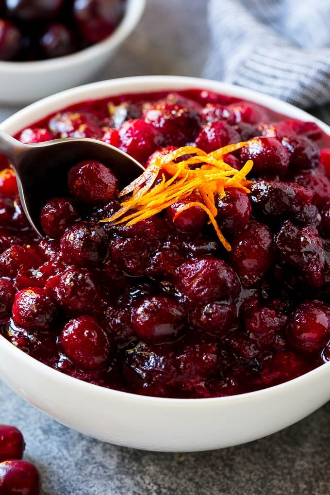 Cranberry Orange Sauce Recipe | Homemade Cranberry Sauce | Fresh Cranberry Sauce #cranberry #orange #fall #thanksgiving #sauce #dinner #edsug A serving spoon in a bowl of cranberry orange sauce.