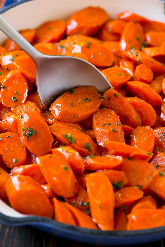 Glazed Carrots Recipe | Brown Sugar Carrots | Carrot Side Dish #carrots #brownsugar #sidedish #glutenfree #thanksgiving #fall #dinner #edsug Glazed carrots in a skillet with a serving spoon.