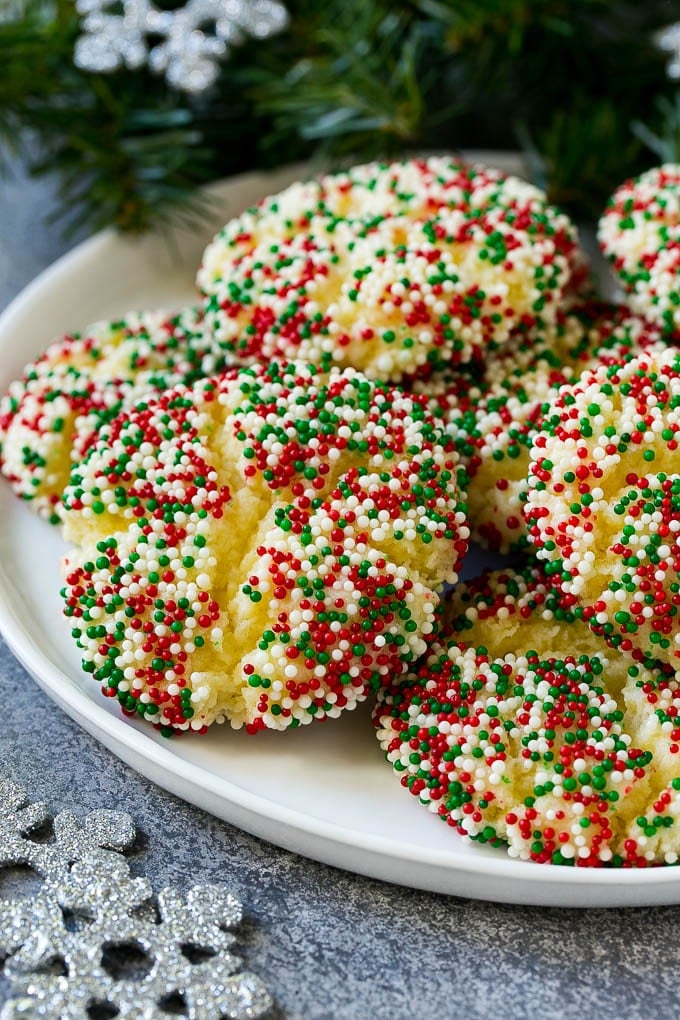 Gooey Butter Cookies Recipe | Cake Mix Cookies | Sprinkle Cookies | Christmas Cookies #cookies #butter #sprinkles #christmas #dessert #baking #edsug A plate of gooey butter cookies covered in holiday sprinkles.