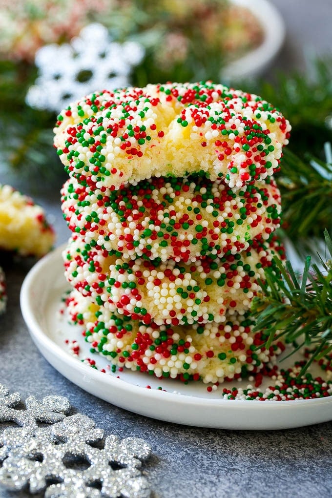 Gooey Butter Cookies Recipe | Cake Mix Cookies | Sprinkle Cookies | Christmas Cookies #cookies #butter #sprinkles #christmas #dessert #baking #edsug A stack of gooey butter cookies with a bite taken out of one.
