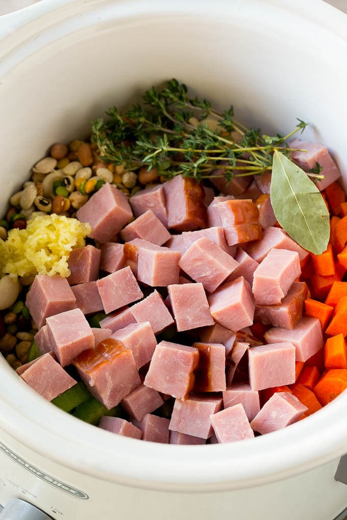 Ham and Bean Soup Recipe | Slow Cooker Ham and Bean Soup | Crockpot Ham and Bean Soup | Leftover Ham Recipe #ham #beans #soup #slowcooker #crockpot #dinner #edsug Vegetables, pork, herbs and garlic in the slow cooker.