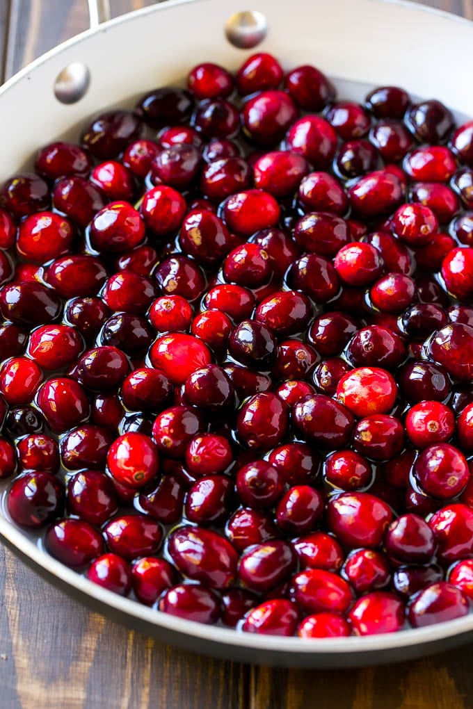 This homemade cranberry sauce is a 6 ingredient recipe that's made with fresh cranberries, sugar and a hint of spice. Cranberries with sugar and water in a skillet.