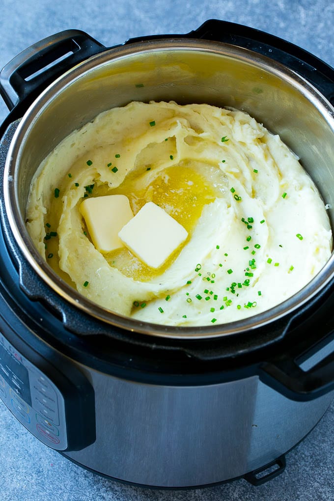 Instant Pot Mashed Potatoes Recipe | Pressure Cooker Mashed Potatoes | Easy Mashed Potatoes #potatoes #sidedish #instantpot #thanksgiving #dinner #edsug Instant Pot mashed potatoes with butter and chives inside a pressure cooker.