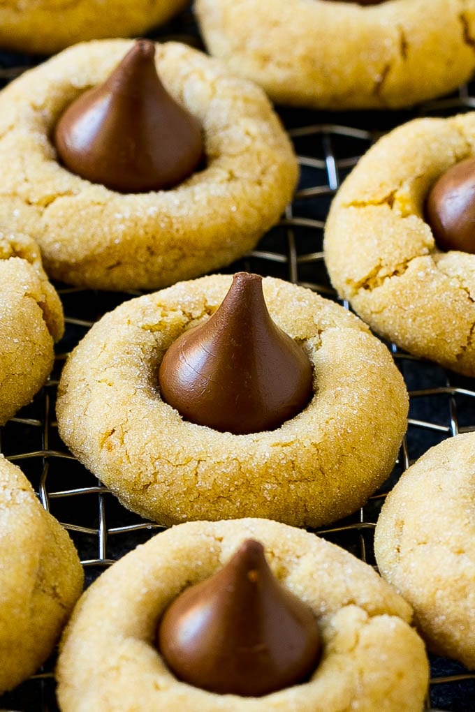 Peanut Butter Blossoms Recipe | Hershey Kiss Cookies | Chocolate Peanut Butter Cookies #cookies #peanutbutter #chocolate #dessert #baking #christmas #christmascookies #edsug Peanut butter blossom cookies on a cooling rack.