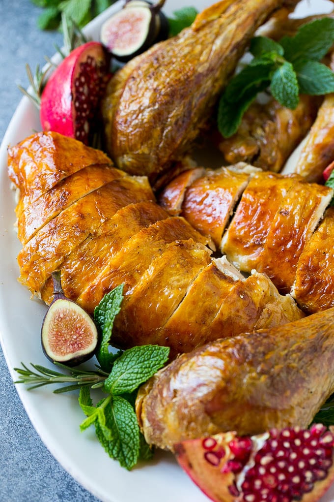 Roast Turkey Recipe | Thanksgiving Turkey | Holiday Turkey | Baked Turkey #turkey #thanksgiving #christmas #dinner #glutenfree #edsug Sliced roast turkey on a serving platter with rosemary, pomegranate and figs.