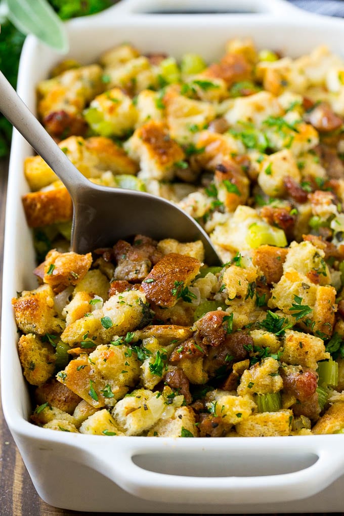 Sausage Stuffing Recipe | Thanksgiving Stuffing | Make Ahead Stuffing #stuffing #thanksgiving #sausage #sidedish #dinner #edsug A baking dish of sausage stuffing with a serving spoon in it.