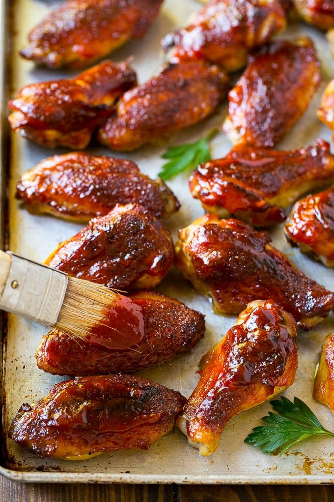 Smoked Chicken Wings | Barbecue Chicken Wings | BBQ Chicken Wings #chicken #wings #bbq #barbecue #appetizer #dinner #edsug BBQ sauce brushed onto a sheet pan of smoked chicken wings.