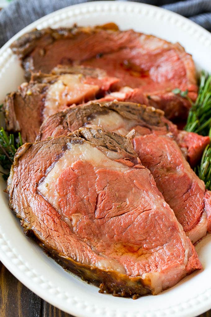 Smoked Prime Rib Recipe | Easy Prime Rib | Smoked Beef | Holiday Prime Rib #primerib #beef #smoker #dinner #edsug #christmas #thanksgiving #lowcarb #keto Slices of beef garnished with fresh herbs.